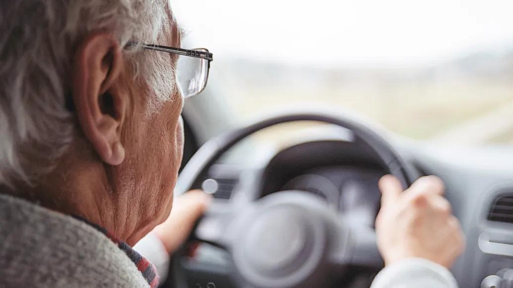 older man driving car behind wheel
