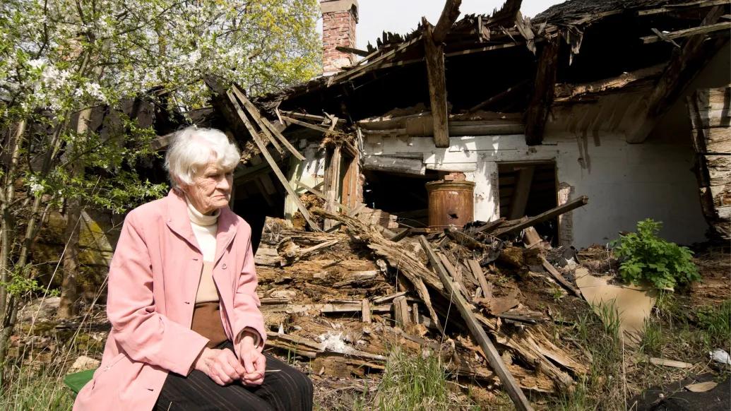 woman sitting outside home destoryed