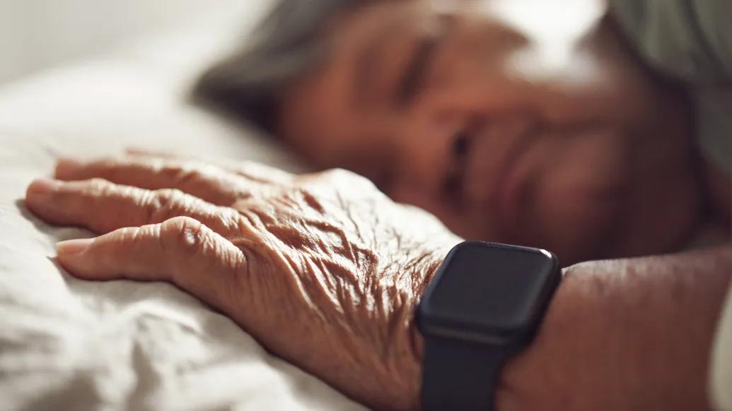 hand on pillow with smartwatch on wrist while person sleeps on pillow