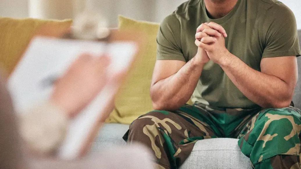 veteran sitting with hands closed with person writing notes across from them