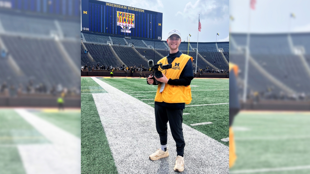 kid on field smiling in UM gear on UM football field