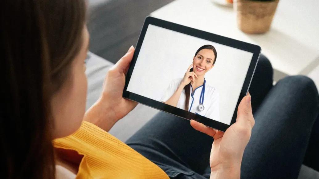 person looking at ipad with provider on screen smiling