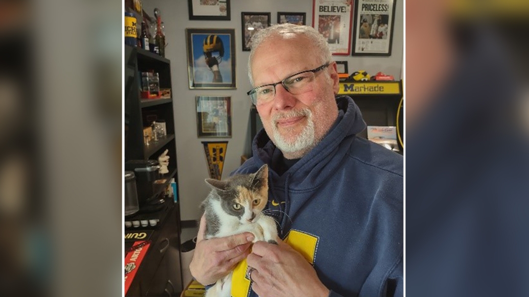 man holding cat in michigan sweater