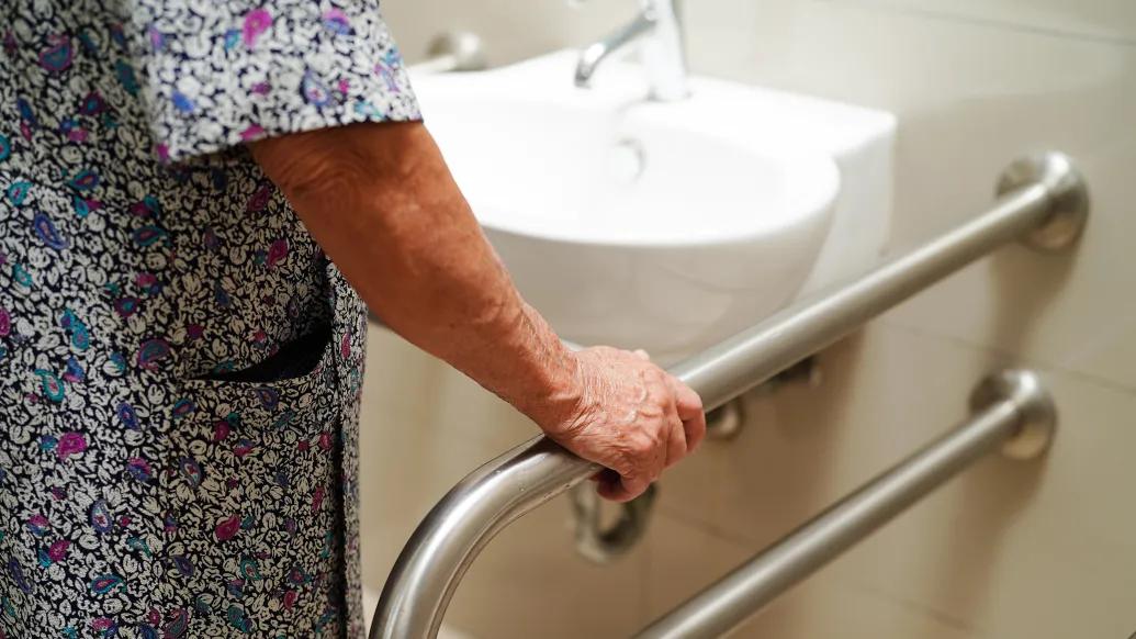woman holding pole in bathroom with patient gown on