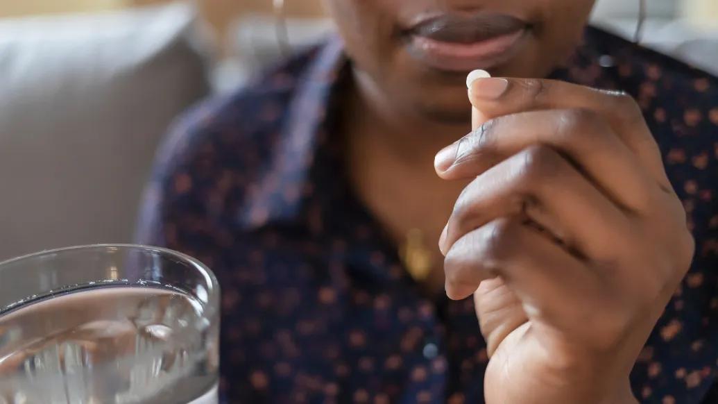 pill being taken close up with water near hand