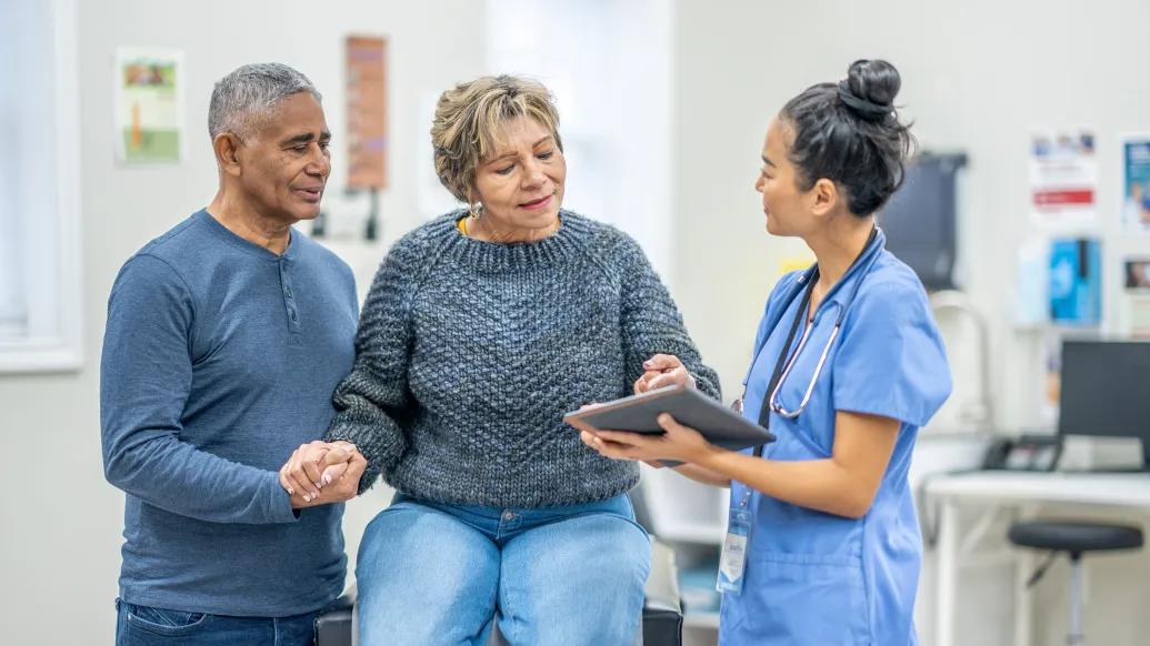older woman with older man with nurse at office