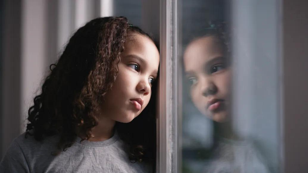 little girl looking sad out the window