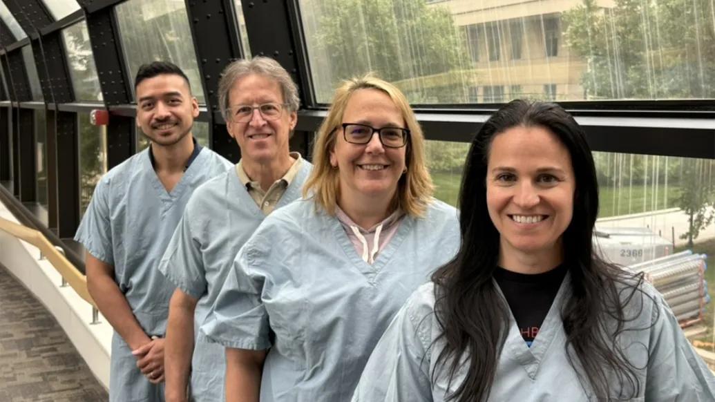 surgeons lined up smiling in tunnel hallway in blue scrubs