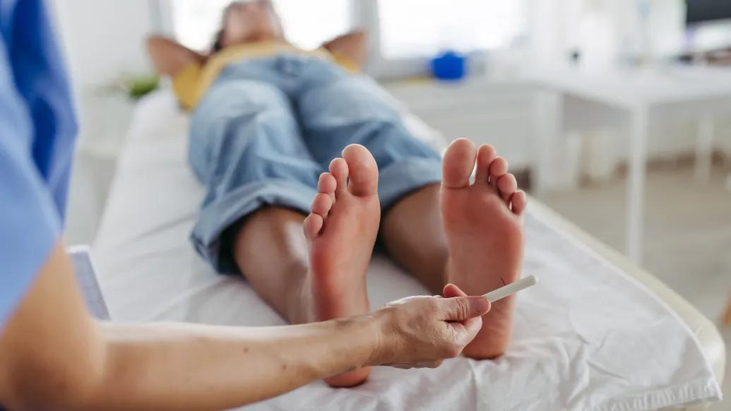 feet on hospital bed and clinician looking at them