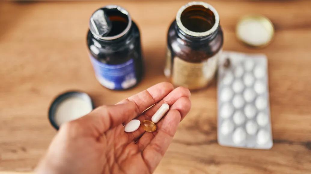pills in hand with pill bottles open