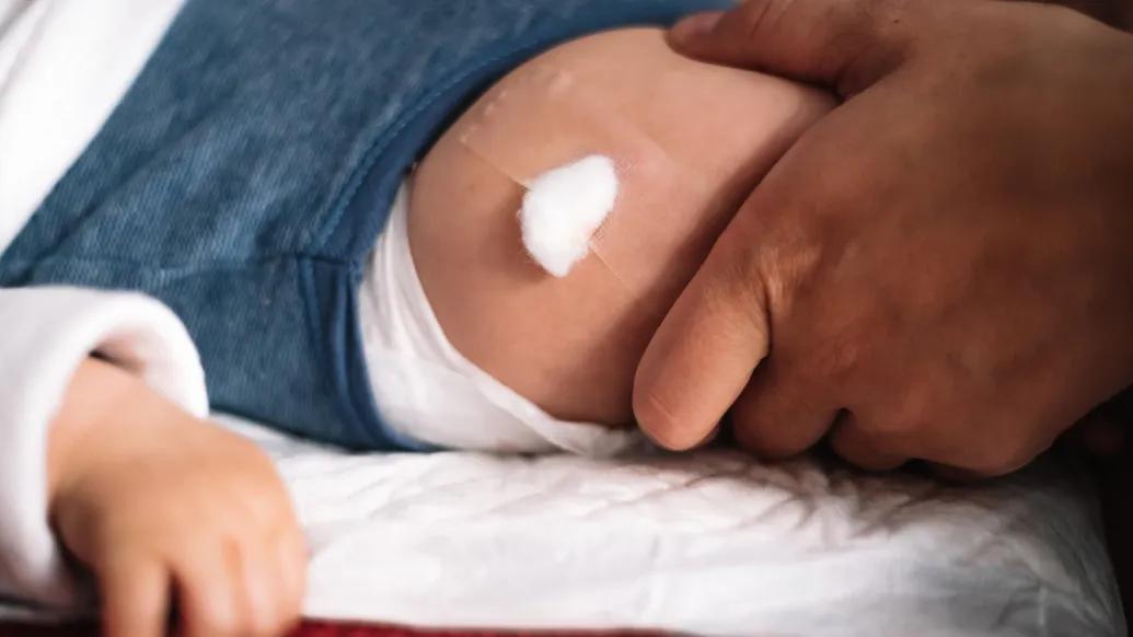 A child's leg with a bandage after receiving a shot.