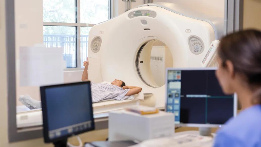 A radiologist talks with a CT scan patient while in the control room.