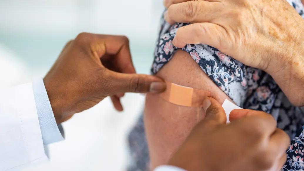 hand putting band aid on persons arm