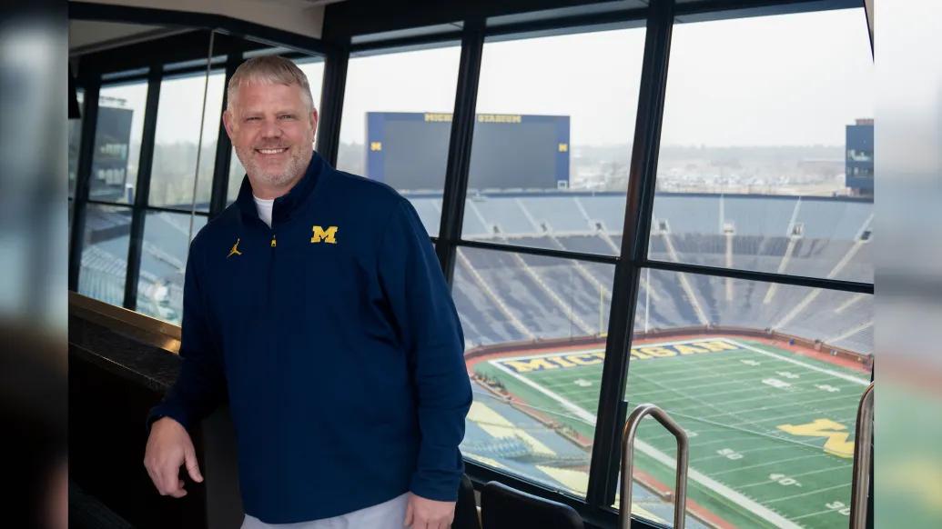Man in a blue pullover against the background of Michigan Stadium