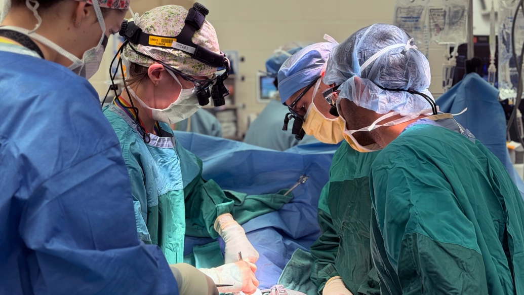 surgeons up close in surgery with scrubs and scrub hats on green teal