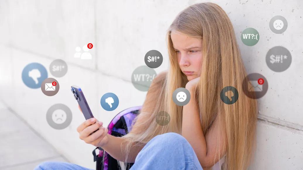 Teen girl sitting on floor next to her bed looking at a smartphone, with icons from social media apps layered over her as she frowns