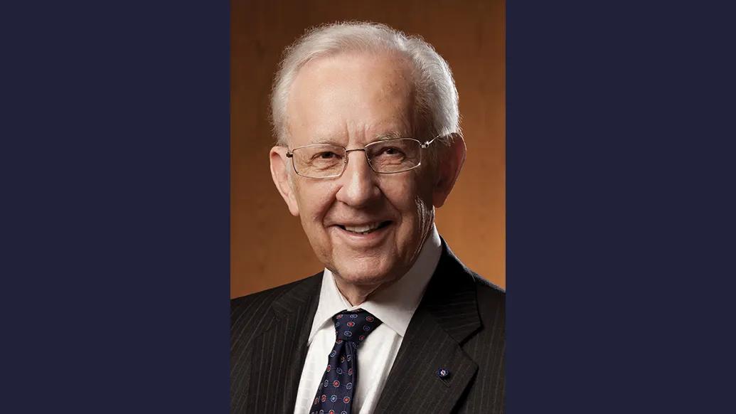 Headshot of Bill Brehm wearing a suit and tie and glasses and smiling