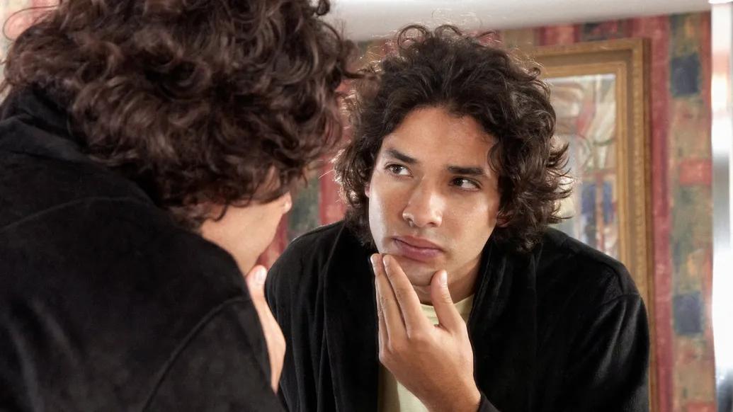man looking in mirror curious at face