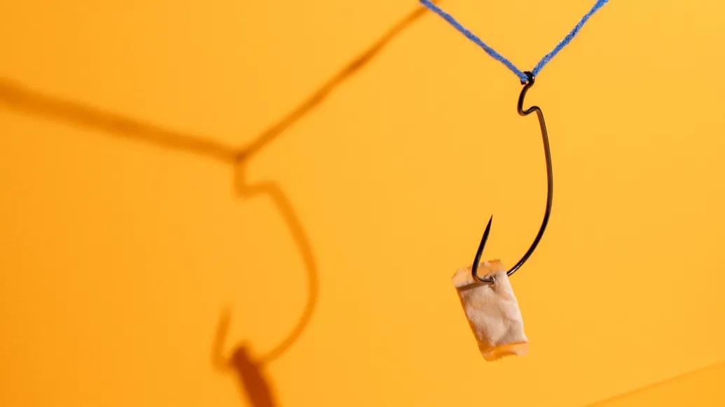 nicotine packet hanging from hook orange background