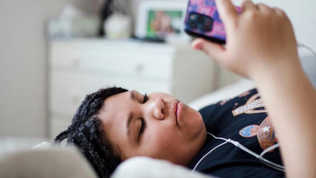 girl looking at phone laying in bed