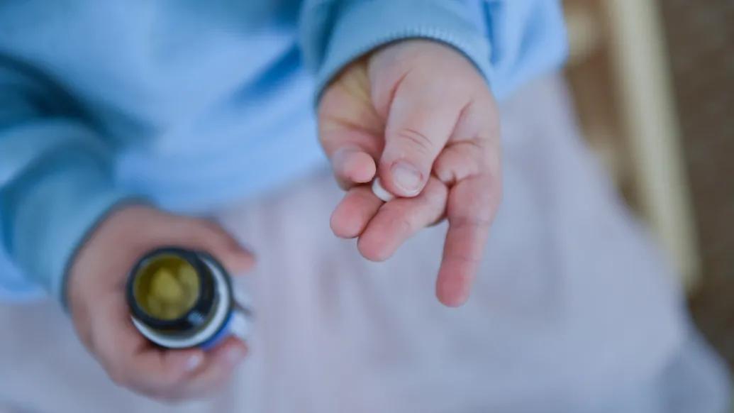 pill in child's hand blue sweater