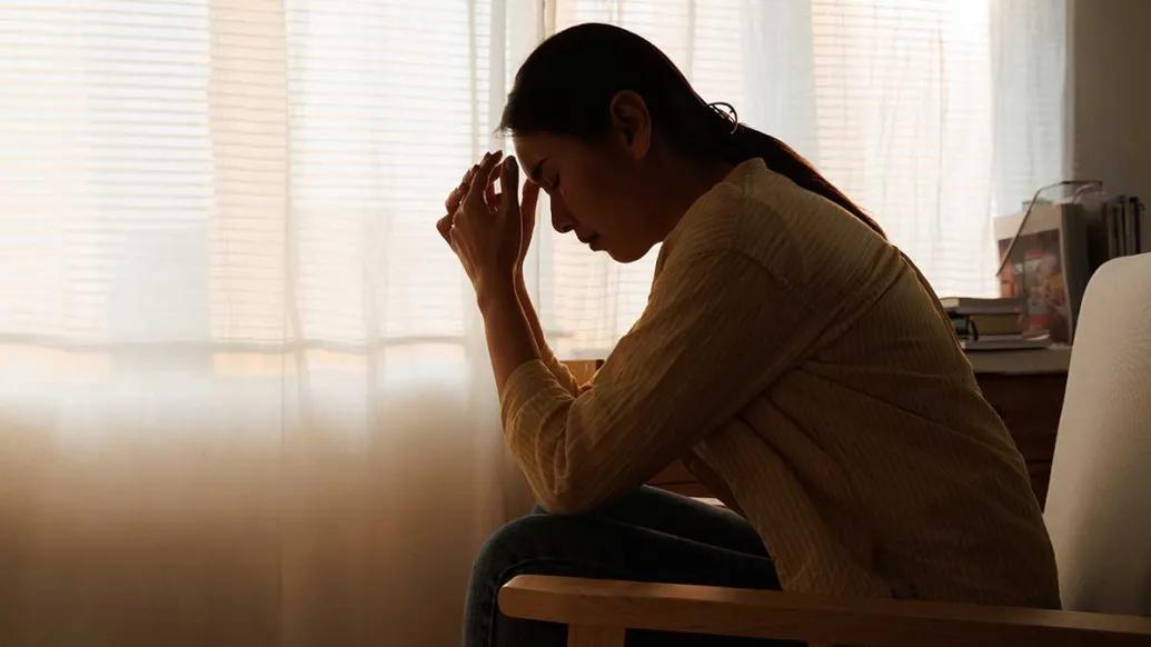 Woman sits with head in hands