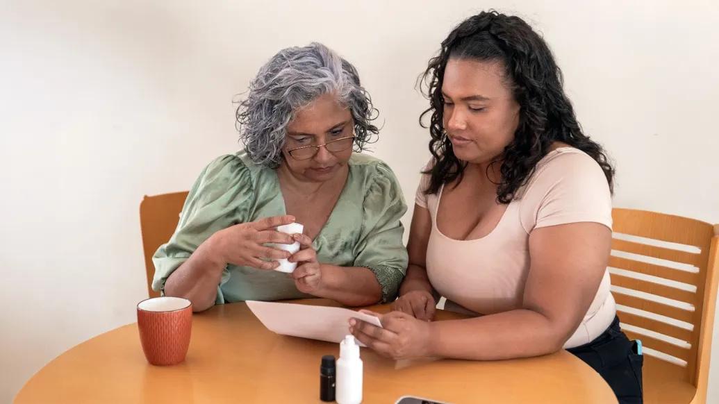 woman with older woman at table helping on tablet