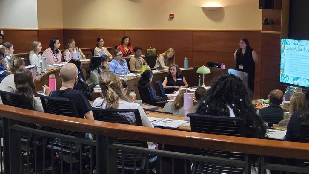 A group of 20+ clinicians attending training in a lecture hall.