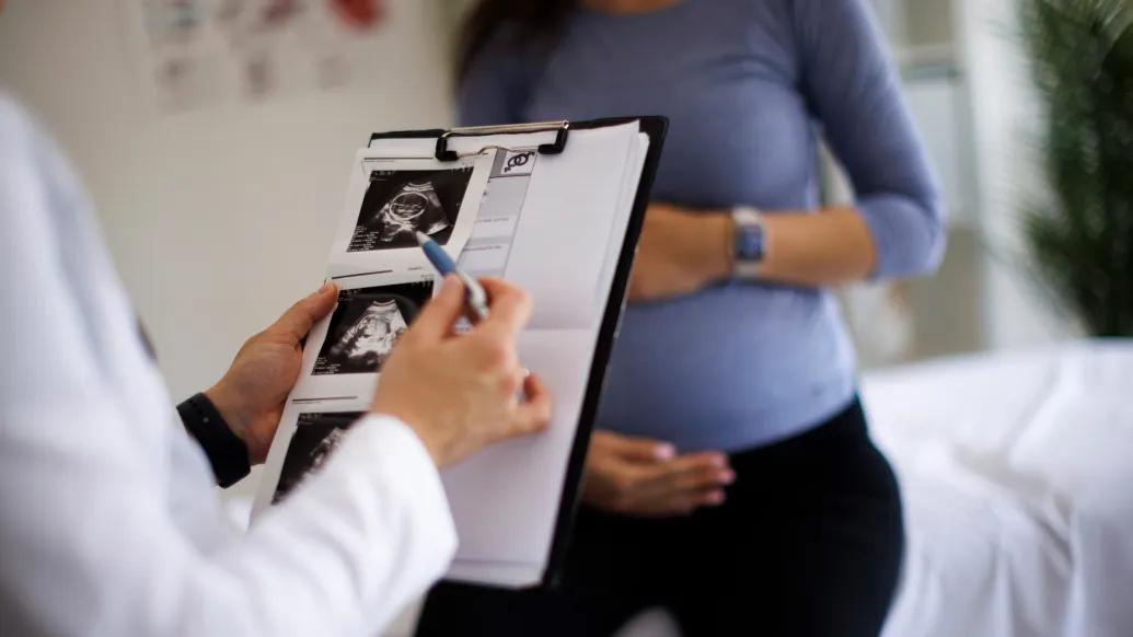chart with sonogram images woman pregnant in background