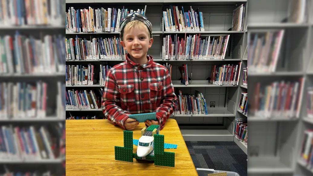 little boy at table smiling in library 