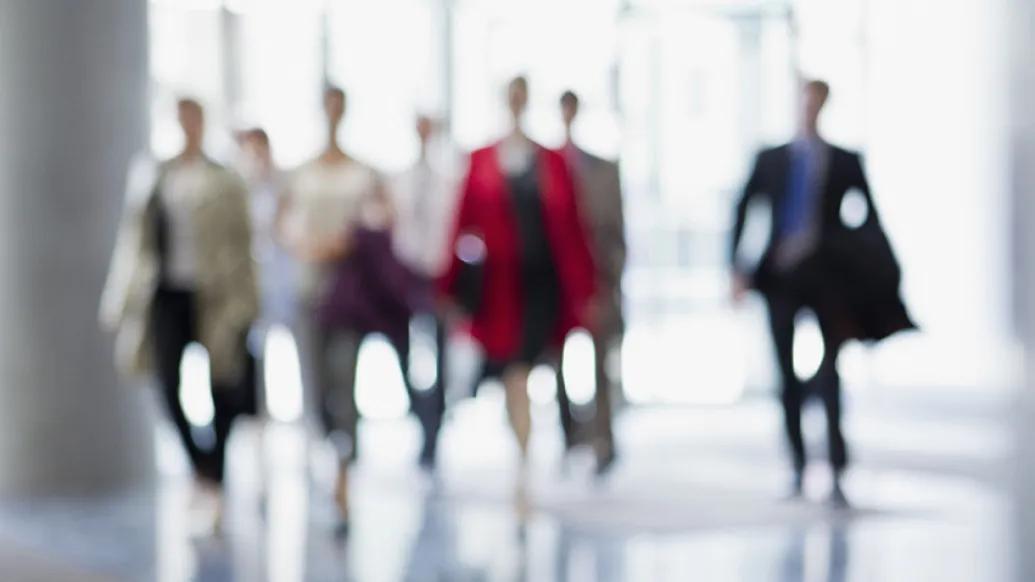 business people walking in white hallway blurred out from a distance