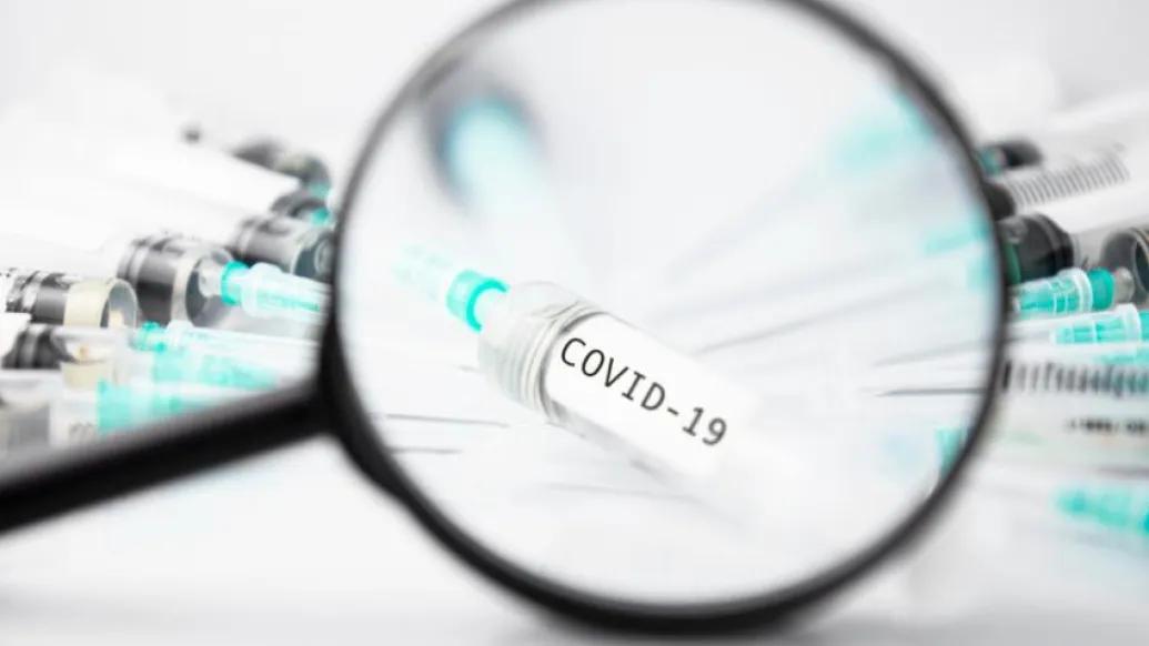 magnifying glass on COVID vaccine Needles