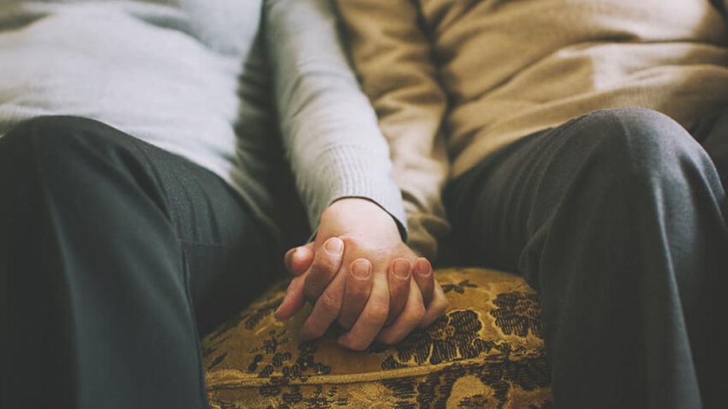 Couple holding hands while sitting low on couch