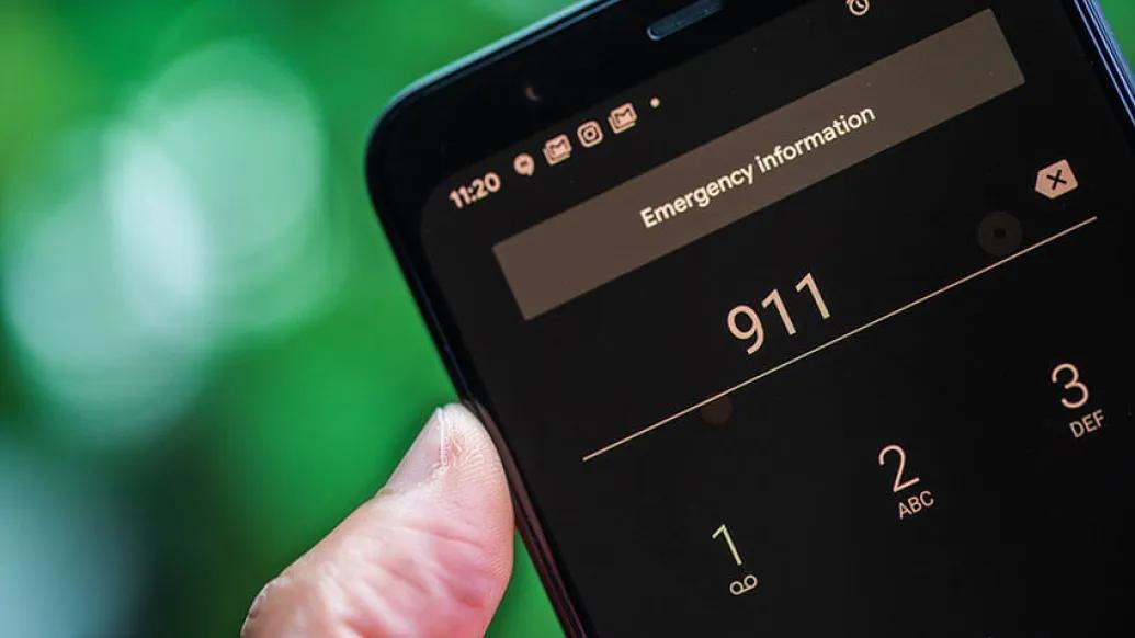 Hand holding cell phone calling 911