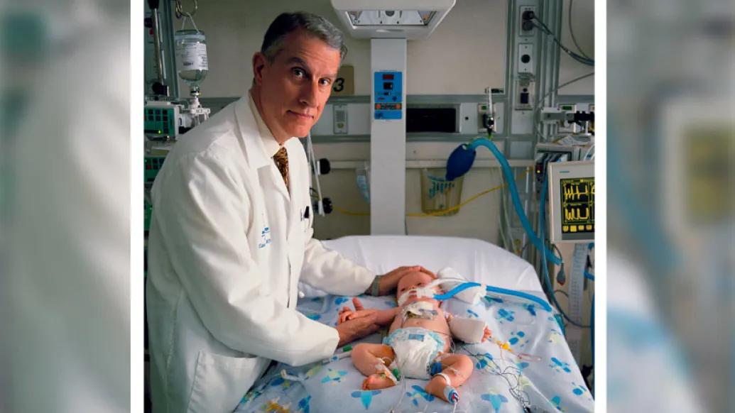 Doctor smiling by bed near baby with tubes