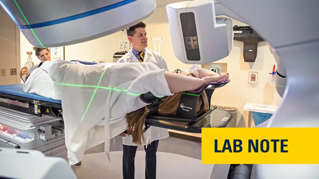 doctor in white coat scanning person in machine with words "lab note" written on yellow badge with blue font bottom right