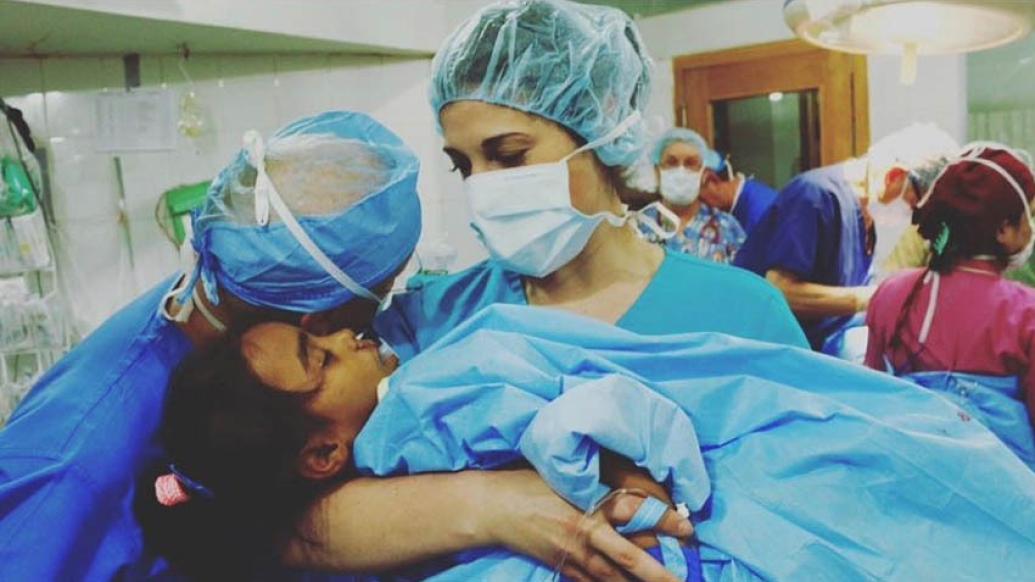 Doctor holding child in surgical gear