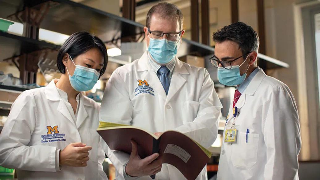 Doctors huddled with masks and labcoats on looking at book