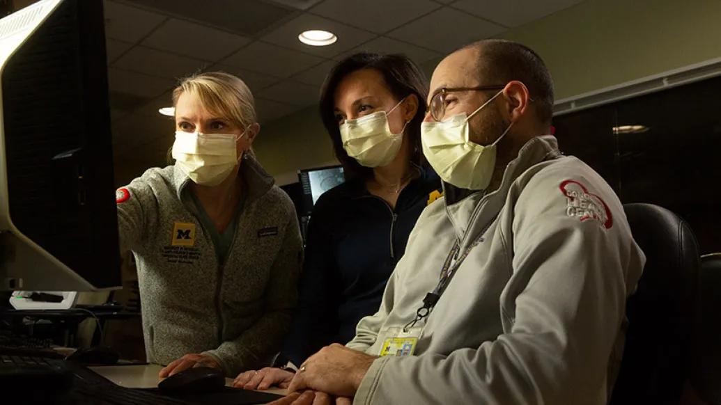 doctors masks pointing computer screen