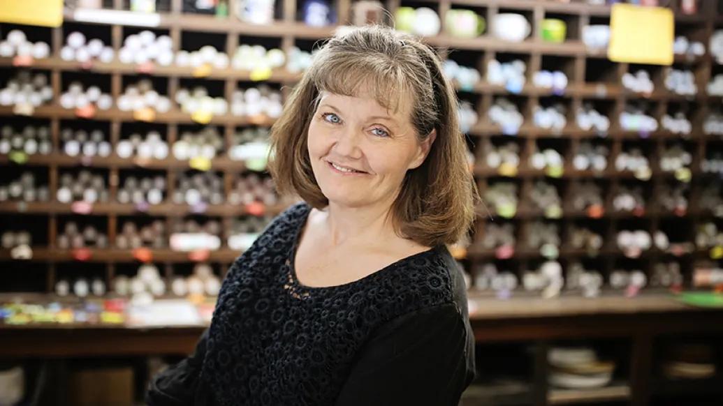 Traci Lawson shelves of art supplies behind her