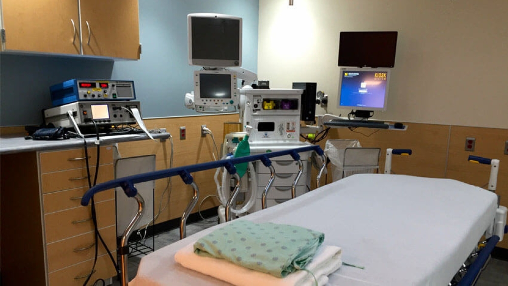 Empty hospital bed with monitors and machines in hospital room