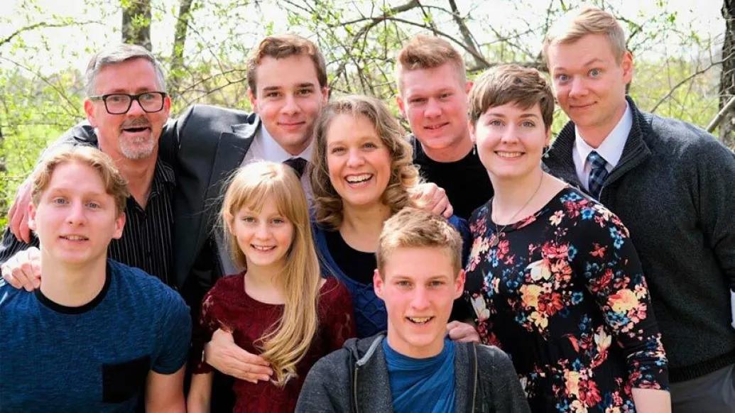 family gathered outside taking a photo in front of trees in nice clothing