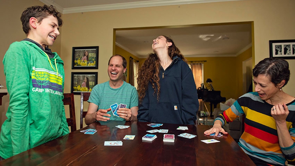 family laughing together at table with game