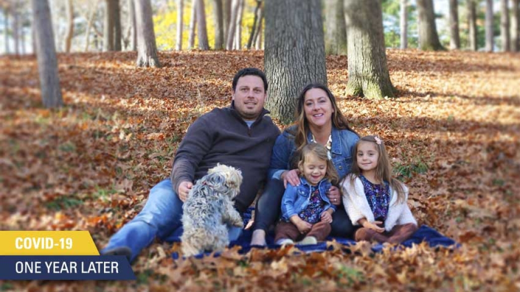 family of 4 with dog sitting against tree on fall leaves