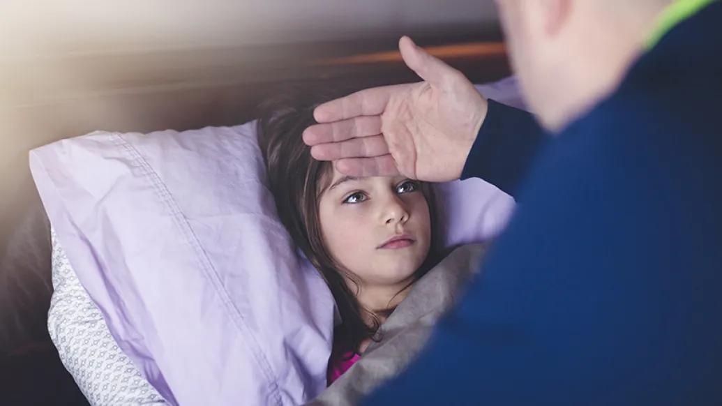 father checking temperature on child in bed