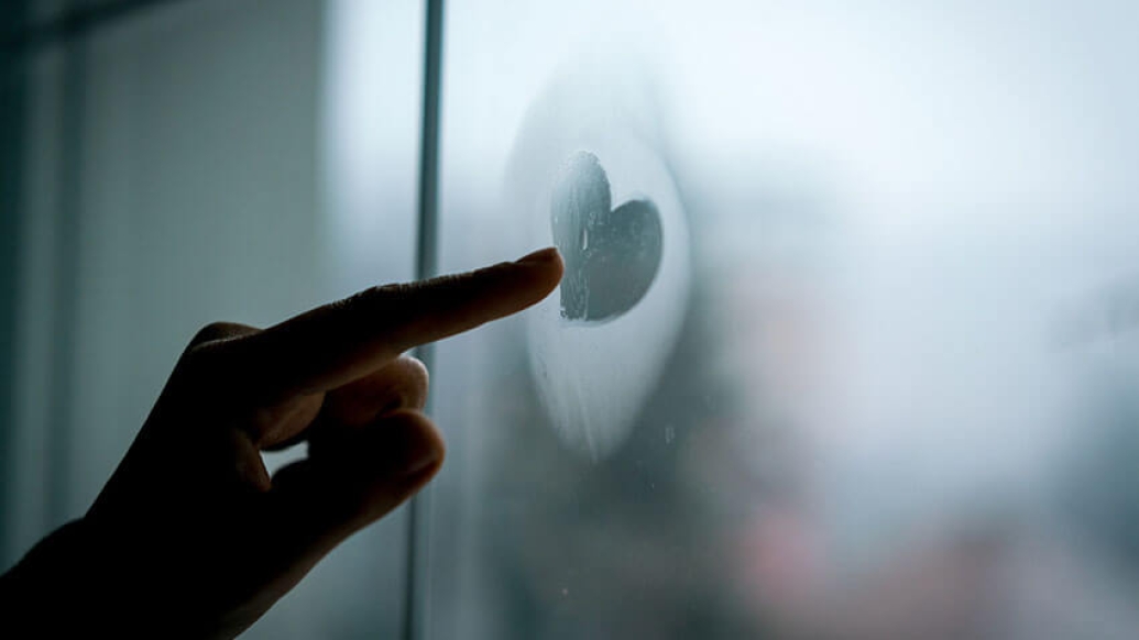 Finger touching heart on foggy window