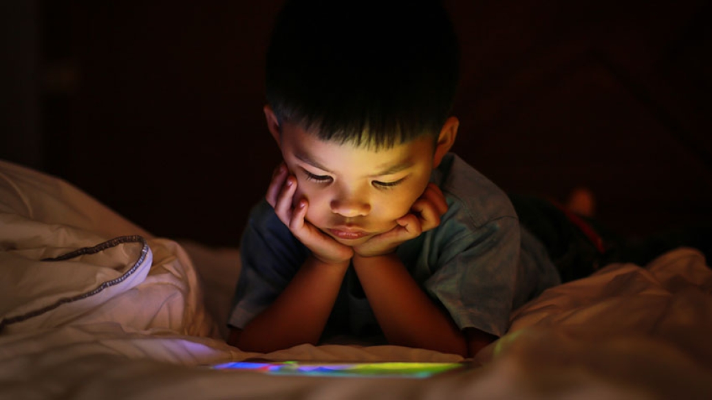 Child with ipad in bed