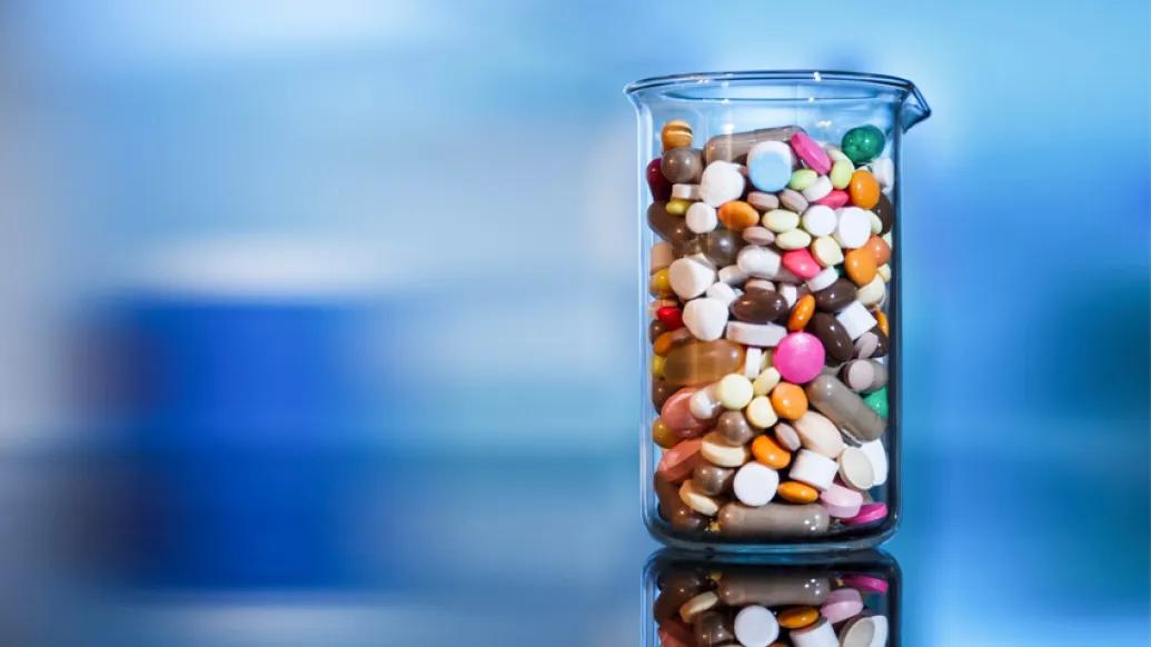 glass beaker filled with colorful pills