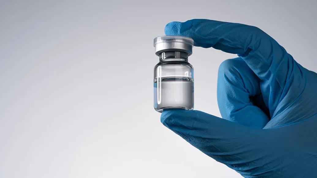 glove hand holding vaccine vial