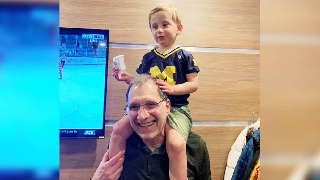 Grandpa with grandson on shoulders near a TV